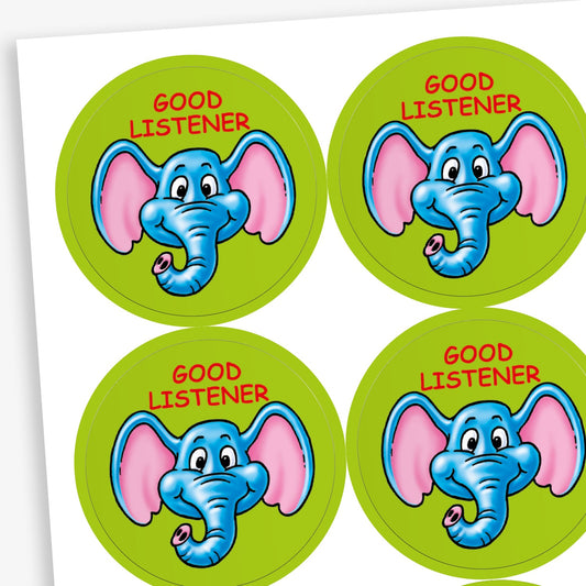 A sheet of circular reward stickers for children. Each sticker has a green background, features a cheerful blue elephant with large pink ears, and the phrase 'GOOD LISTENER' in red text above the illustration.
