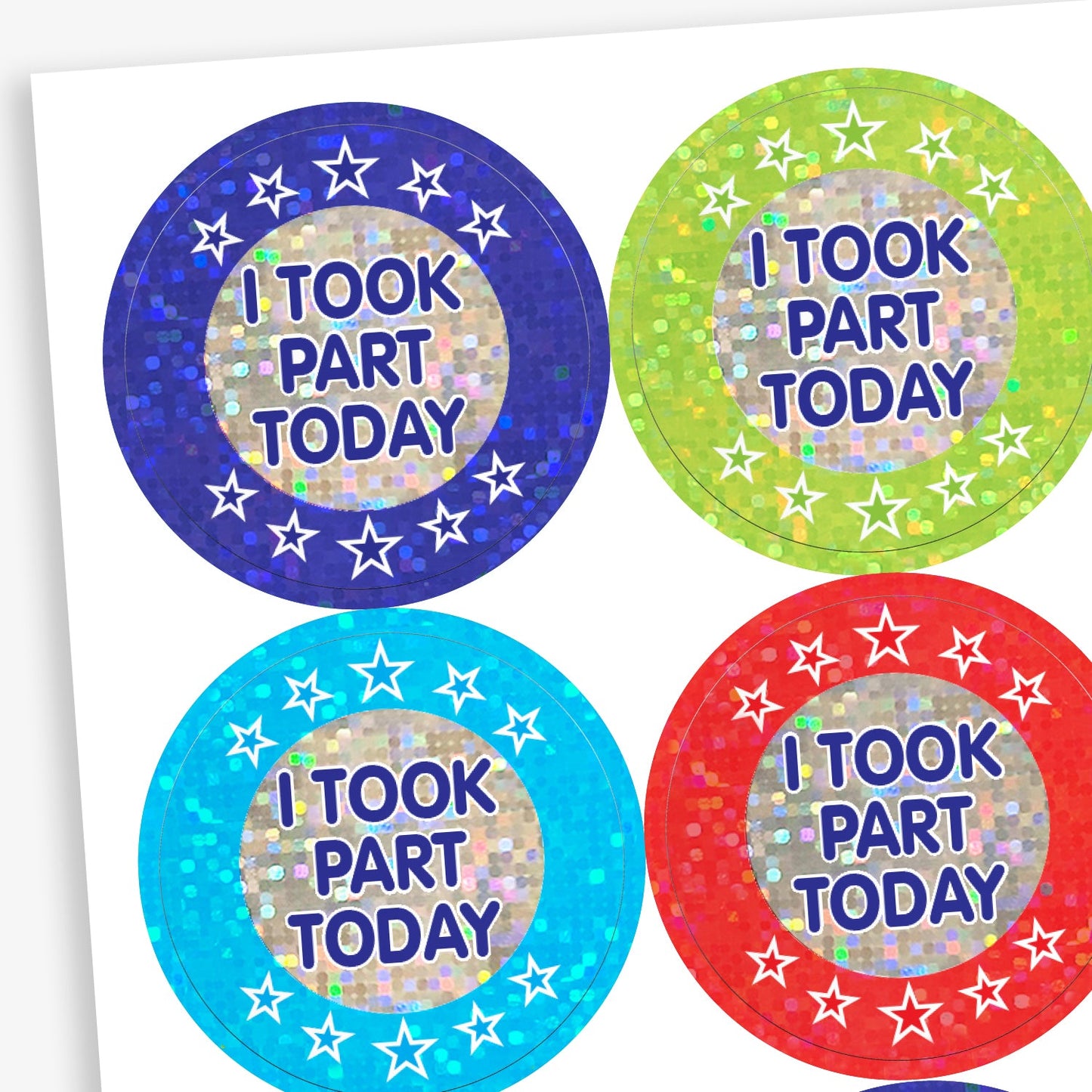 A sheet of holographic circular reward stickers for children, each with a sparkly background and the phrase 'I TOOK PART TODAY' in bold purple letters. Each sticker has a central silver area surrounded by stars and comes in different colours: dark blue, light green, turquoise blue, and red.