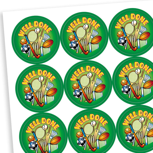 A sheet of circular green reward stickers with the phrase 'WELL DONE' in bold yellow text. Each sticker features a colourful illustration of various sports equipment, including a tennis racket, cricket bat, football, rounders bat, shuttlecock, and whistle, celebrating achievement in sports or physical education.
