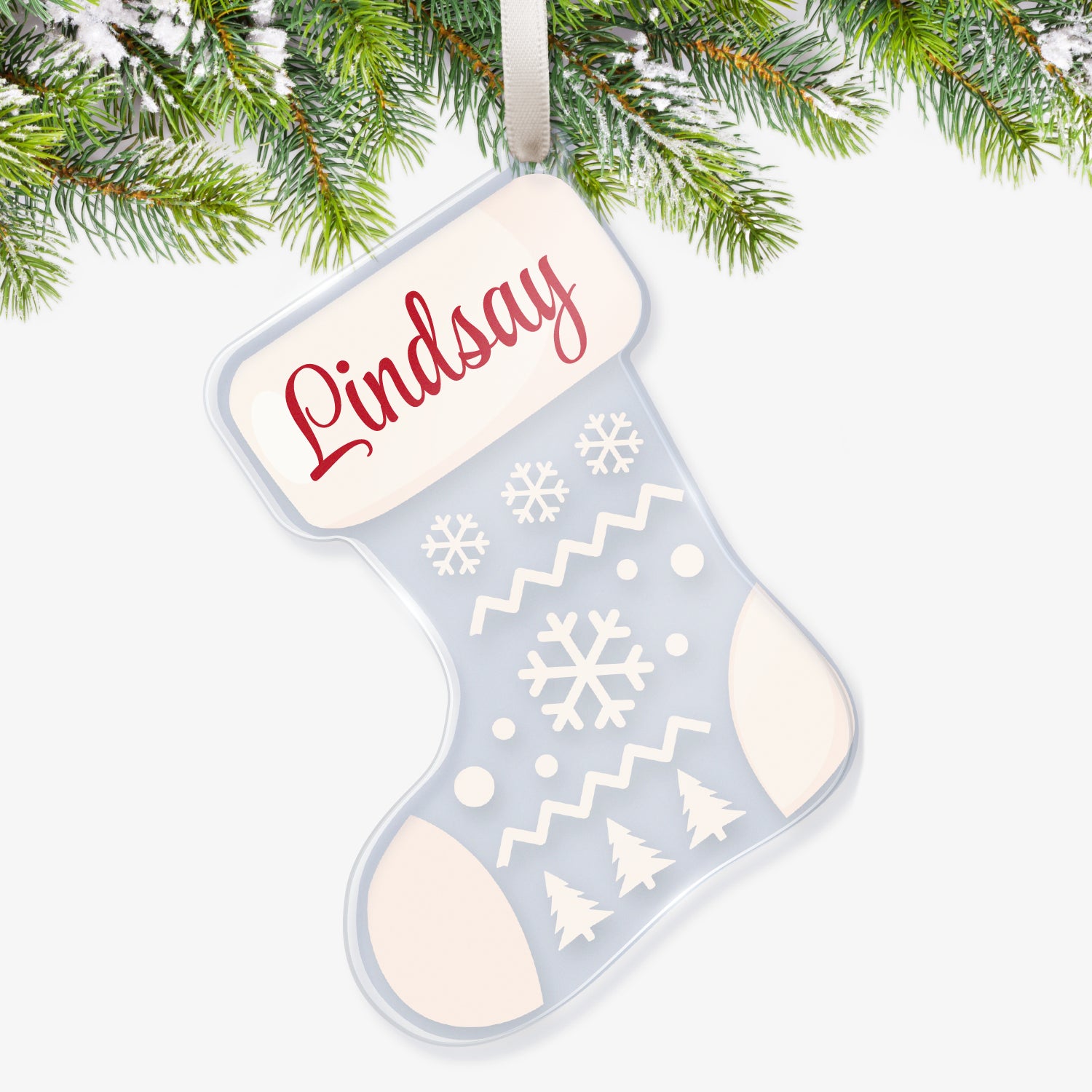 Clear acrylic Christmas stocking-shaped tree ornament decorated with a snow scene with 3 christmas trees and snowflakes in white; The heel, toe and top are white featuring a space at the top for a customisation saying 'Lindsay' in redscript, hanging on a Christmas tree.