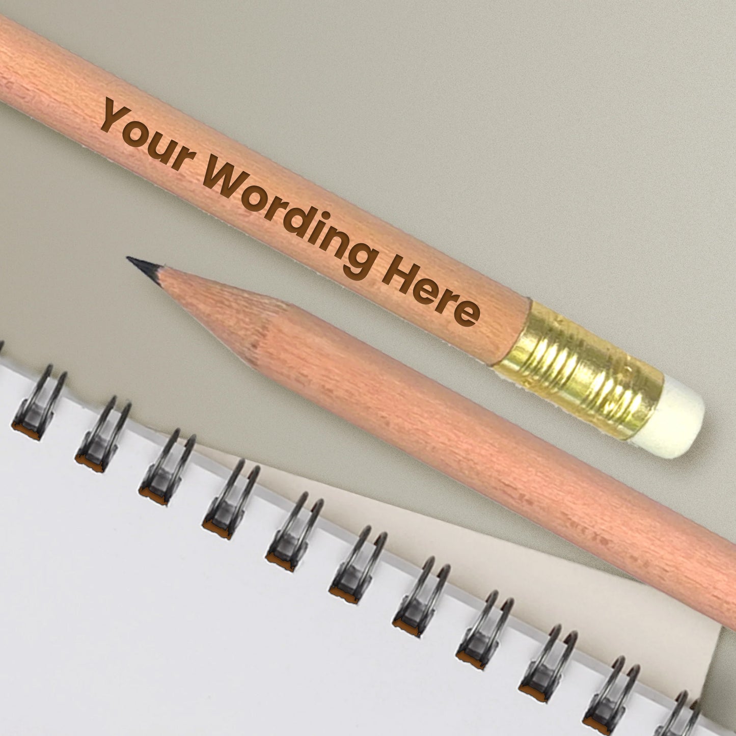Personalised pencil with natural wooden barrel and gold ferrule. Choice of wording etched onto pencil. Shown with notepad.