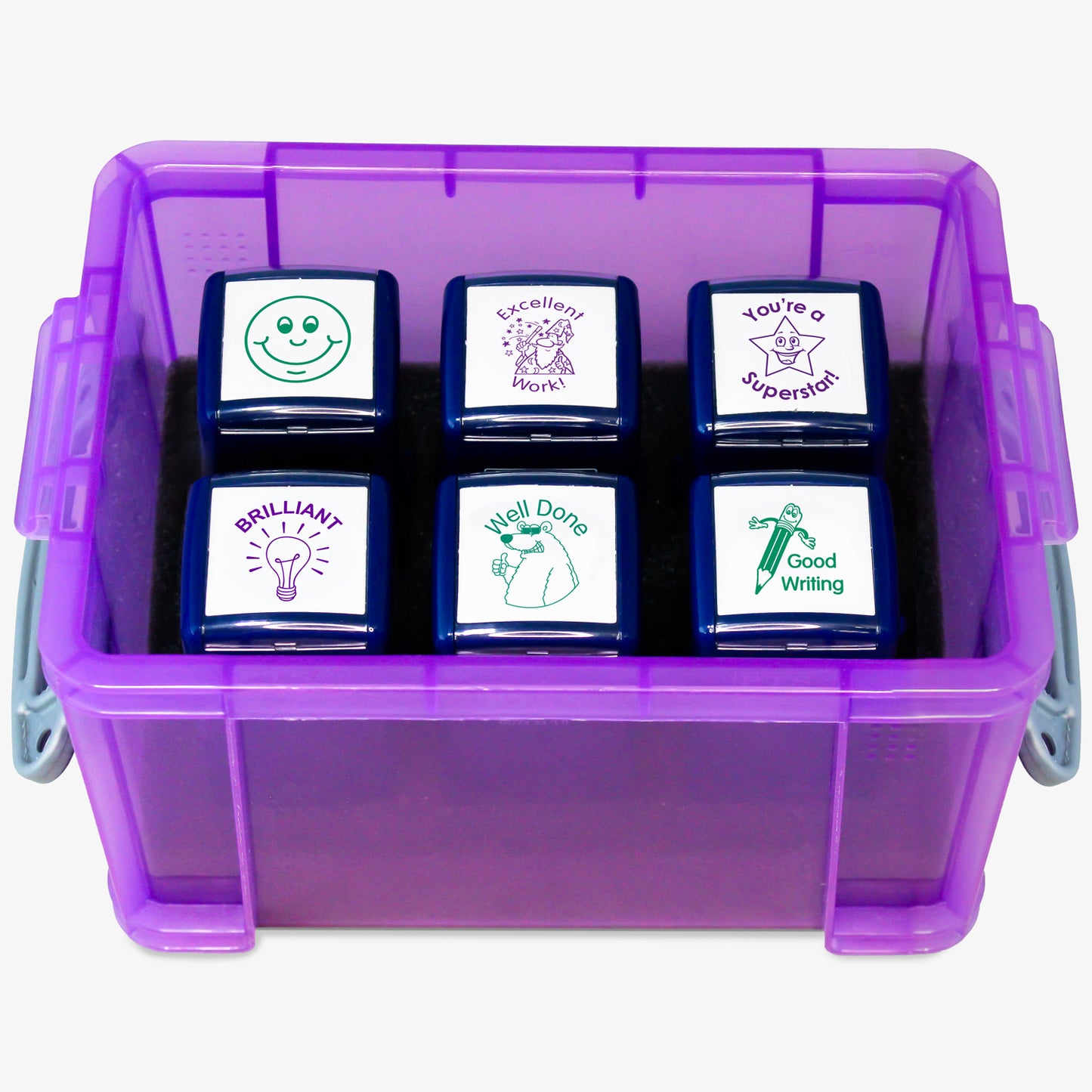 A transparent purple storage box containing six teacher stampers with positive feedback phrases and images. The stamps read: 'BRILLIANT!' with a light bulb, 'Well Done' with a smiling face, 'Good Work' with a pencil, 'Excellent Work' with a star character, 'You're a Superstar!' with a starburst, and a smiley face icon. The clear lid is slightly open, displaying the 'PTS Stampers' label.