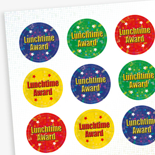 A sheet of colourful circular 'Lunchtime Award' stickers with holographic star backgrounds. Each sticker features the text in bold red or yellow font, set against various colours including blue, green, red, and yellow.