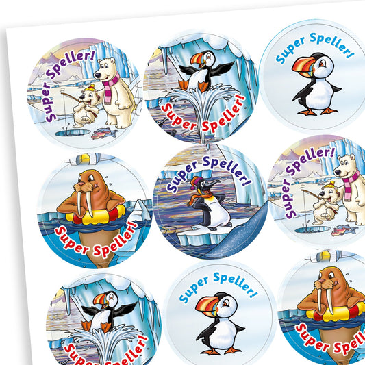 A sheet of circular reward stickers with the phrase 'Super Speller!' in blue or red text. Each sticker features arctic-themed cartoon animals such as puffins, polar bears, and walruses, engaging in playful or reading-related activities against icy, snowy backdrops. The designs are colourful and cheerful, celebrating spelling achievement.