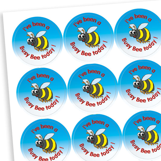 A sheet of circular reward stickers with a cheerful cartoon bee and the phrase 'I've been a Busy Bee today!' written in red text. Each sticker has a bright blue gradient background, highlighting the positive message and the bee's friendly expression.