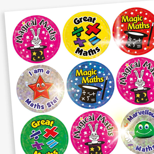 A sheet of holographic colourful round stickers with maths-themed praise. Including a pink sticker with a rabbit in a magician's hat and the phrase 'Magical Maths', a yellow sticker with maths symbols and the words 'Great Maths', a red sticker with a magician’s hat and the phrase 'Magic Maths', and a silver sticker with a smiling star and the phrase 'I am a Maths Star'.