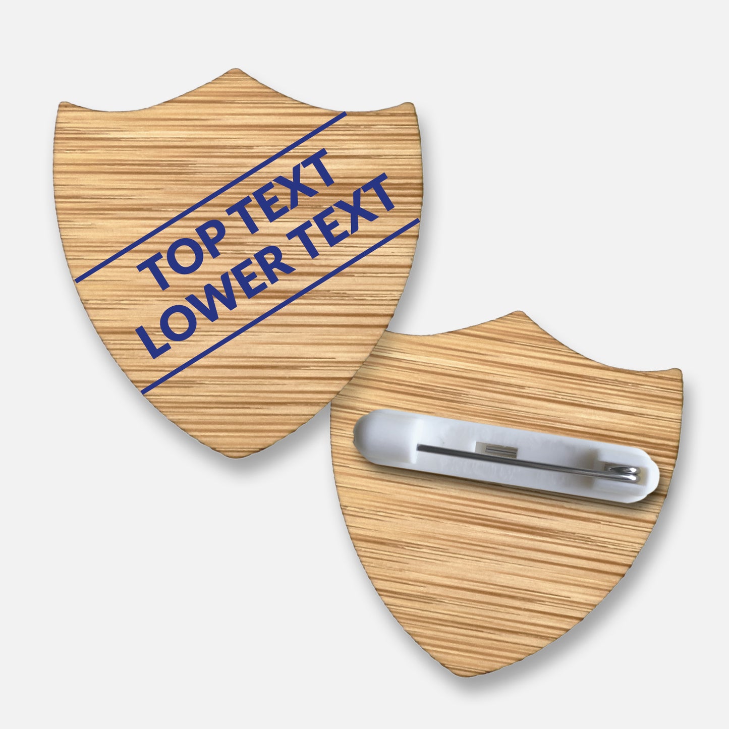A 34mm x 36mm shield-shaped badge made from sustainable bamboo with a coloured or natural wood grain finish. The front displays two lines of customisable text printed diagonally in bold font with colour options. The reverse side is equipped with a secure metal pin fastening. This eco-friendly badge is ideal for recognising pupil roles, house affiliations, or achievements in educational settings.