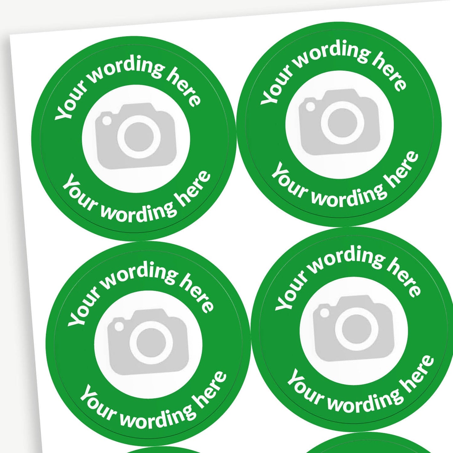 A sheet of circular stickers with a green outer border and a central white centre with a camera icon to indicate customisation.  In the border the placeholder text 'Your wording here' arcs above and below the icon.