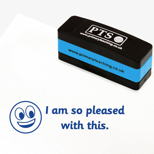 44mm x 13mm self-inking stamper featuring the phrase 'I am so pleased with this.' in bold blue letters nexts to an illustration of a grinning face.