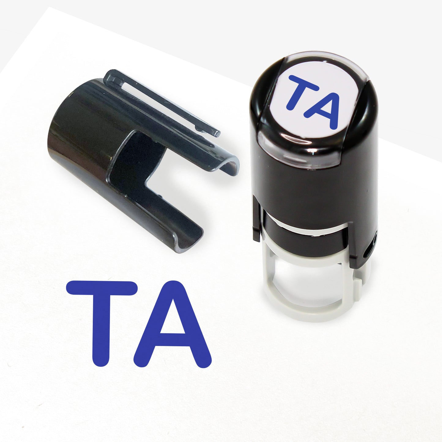 A 10mm self-inking stamp with blue letters 'TA' central to the design.  The stamper lid also shows a clip for attaching the stamper to a lanyard.