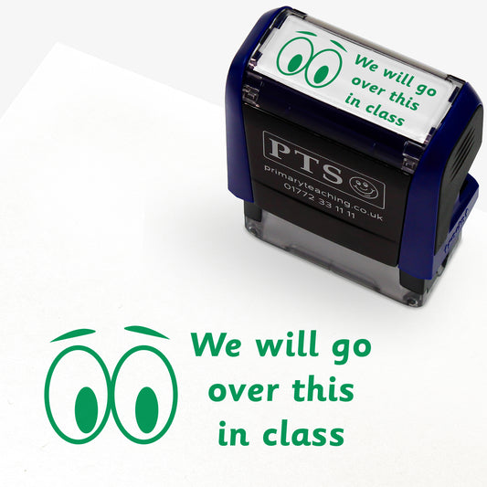 A rectangular pre-inked teacher stamper measuring 38mm x 15mm, featuring a green ink impression of two cartoon eyes beside the phrase "We will go over this in class" in a playful, rounded font. The stamper has a dark blue casing with the PTS logo and contact details on the front, designed for marking pupils' work to indicate topics to be revisited during class discussions.