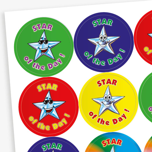 Sheet of round 'Star of the Day' reward stickers featuring smiling cartoon stars with expressive faces. Each sticker has the same message but comes in a variety of vibrant background colours, including green, blue, red, and yellow.