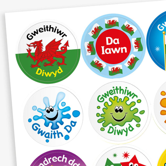 Sheet of Welsh-language reward stickers featuring various colourful designs, including a red Welsh dragon with 'Gweithiwr Diwyd', a roundel with Welsh flags and 'Da Iawn', a smiling paint splash with 'Gwaith Da', and a green germ character also labelled 'Gweithiwr Diwyd'.