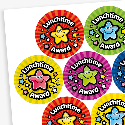 A sheet of colourful, fruit scented, circular 'Lunchtime Award' stickers featuring smiling cartoon stars in different colours, including yellow, red, blue, green, and pink. Each sticker has a striped or patterned background with scattered stars.