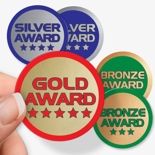 Gold, Silver, and Bronze award badges held by a hand on a white background