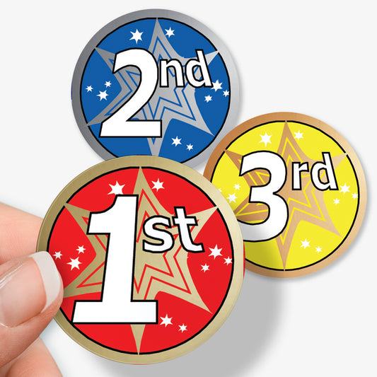 Three colorful badges with numbers and letters, held by a hand on a white background.