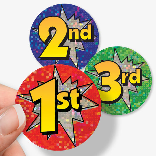 Three colorful stickers with numbers 1st, 2nd, and 3rd held by a hand on a white background.