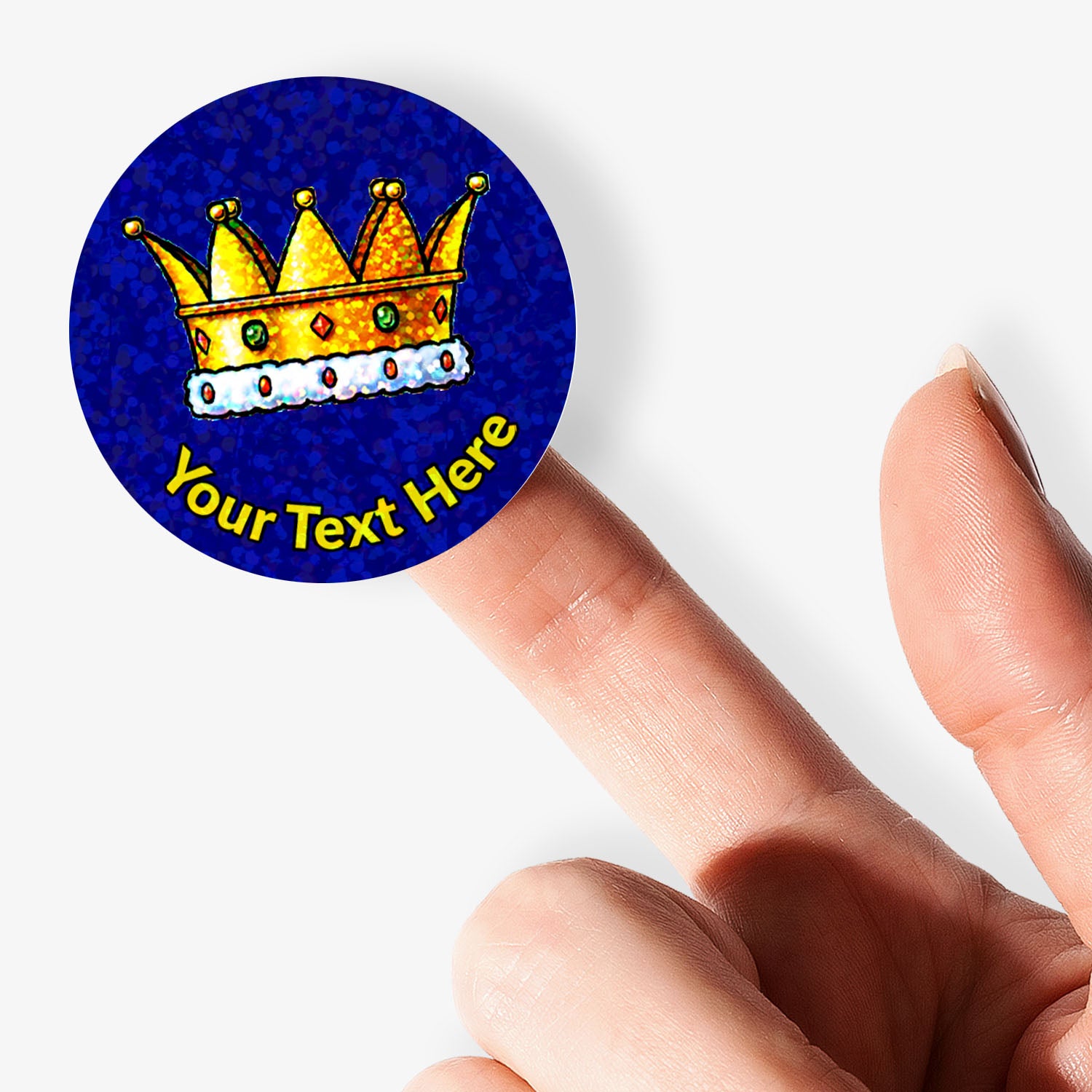 Round blue sticker with a gold crown and customizable text held between fingers.