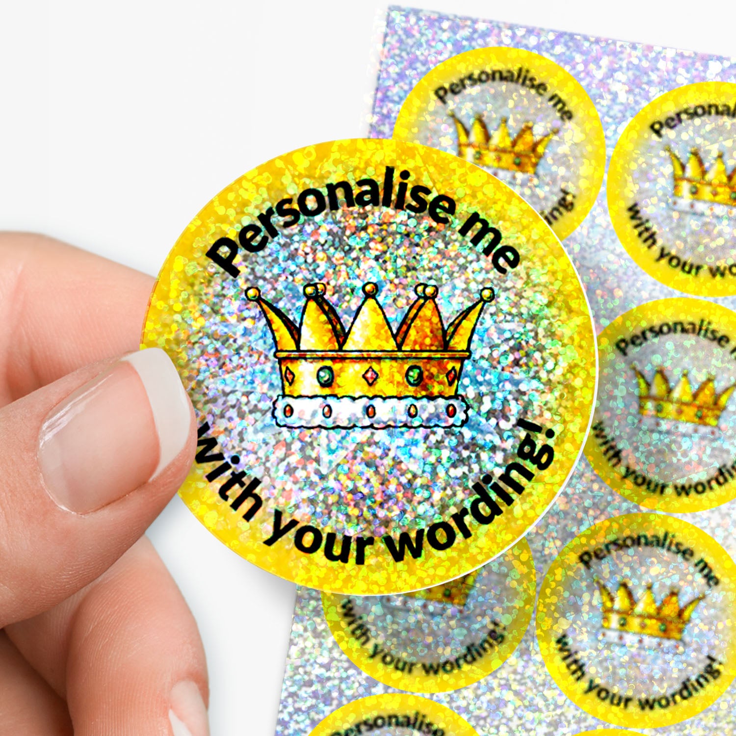 Glittery yellow stickers with a crown design and text 'Personalise me with your wording!' held by a hand.