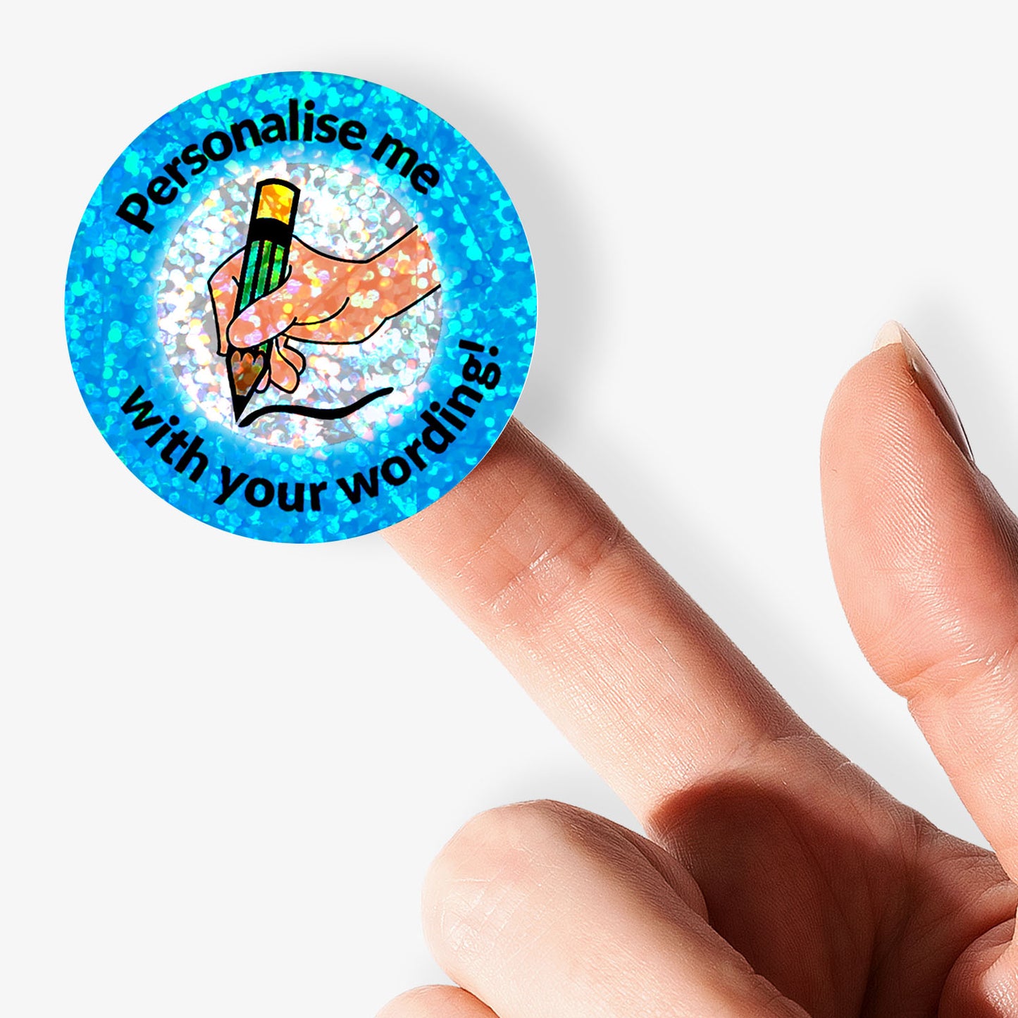 Round blue glittery sticker with text 'Personalise me with your wording' held by a finger on a white background