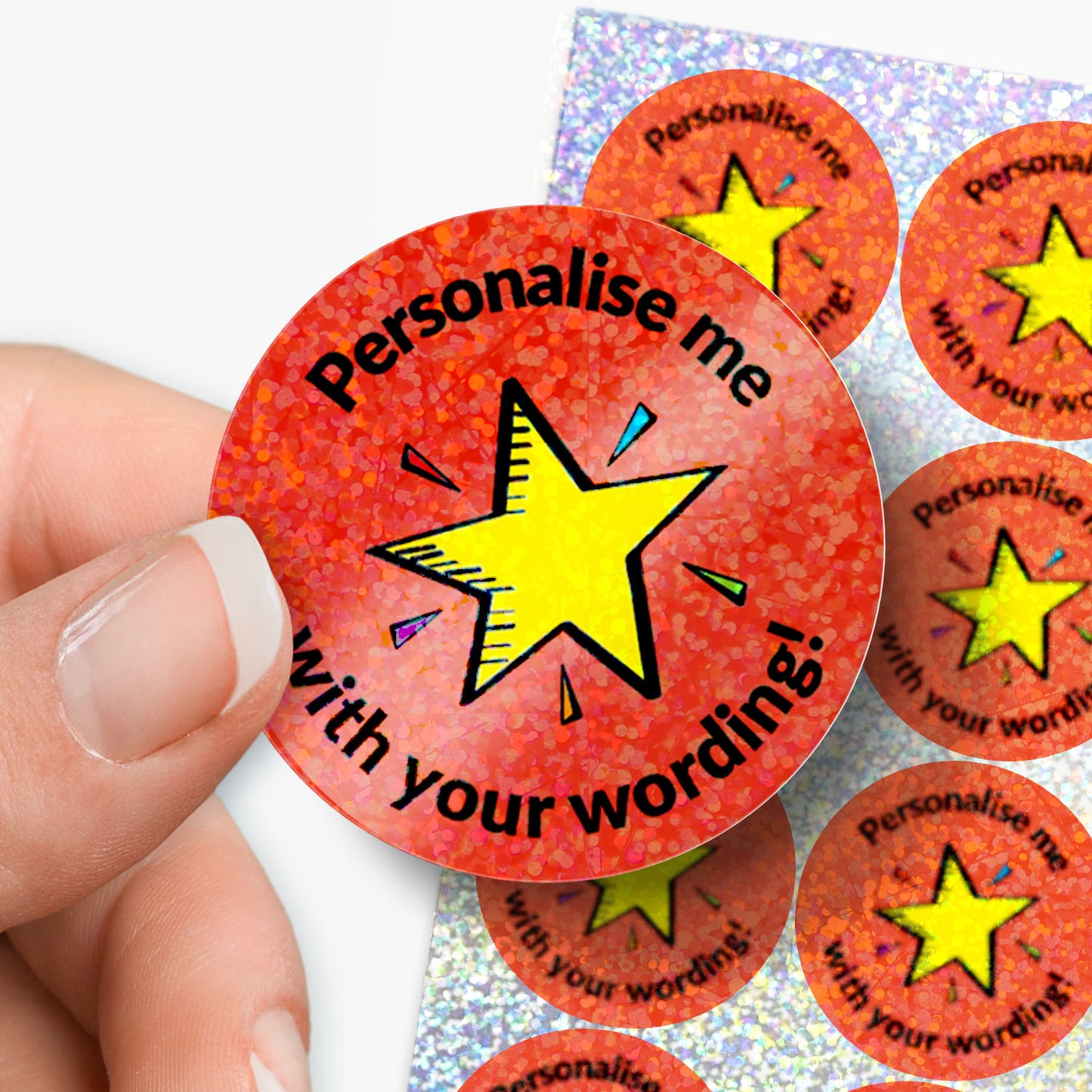 Personalised holographic red sticker with yellow star and text 'Personalise me with your wording!' held by a hand.