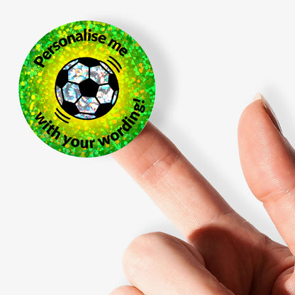 Personalised holographic round green stickers with soccer ball design and text 'Personalise me with your wording!' held by a finger.