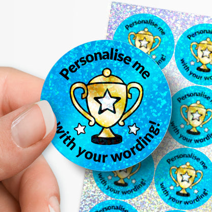 Personalised holographic circular blue sticker with trophy graphic and text 'Personalise me with your wording!' held by a hand.