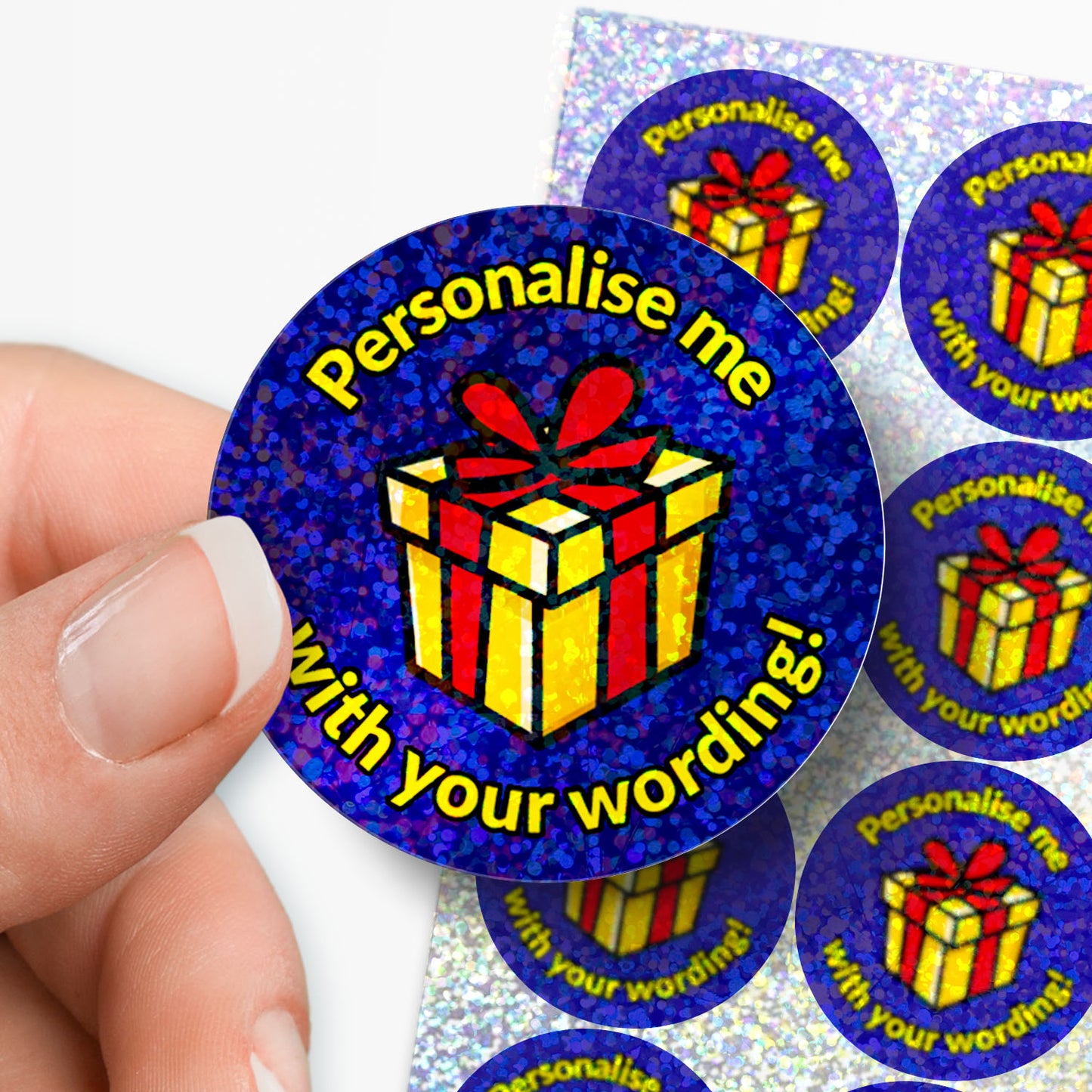 Personalised holographic round sticker with gift box design and text 'Personalise me with your wording!' held by a hand.