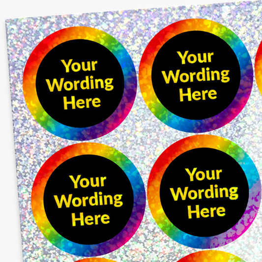 Four round stickers with rainbow borders and yellow text on a silver glitter background
