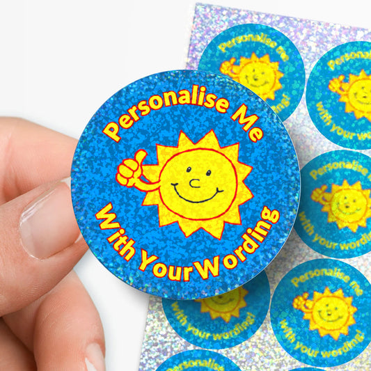 Round blue sticker with sun graphic and text 'Personalise me with your wording!' held by a hand.