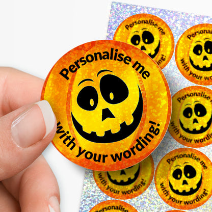 Circular sticker with sparkly pumpkin design and personalised text held by a hand with sheet of stickers in the background.