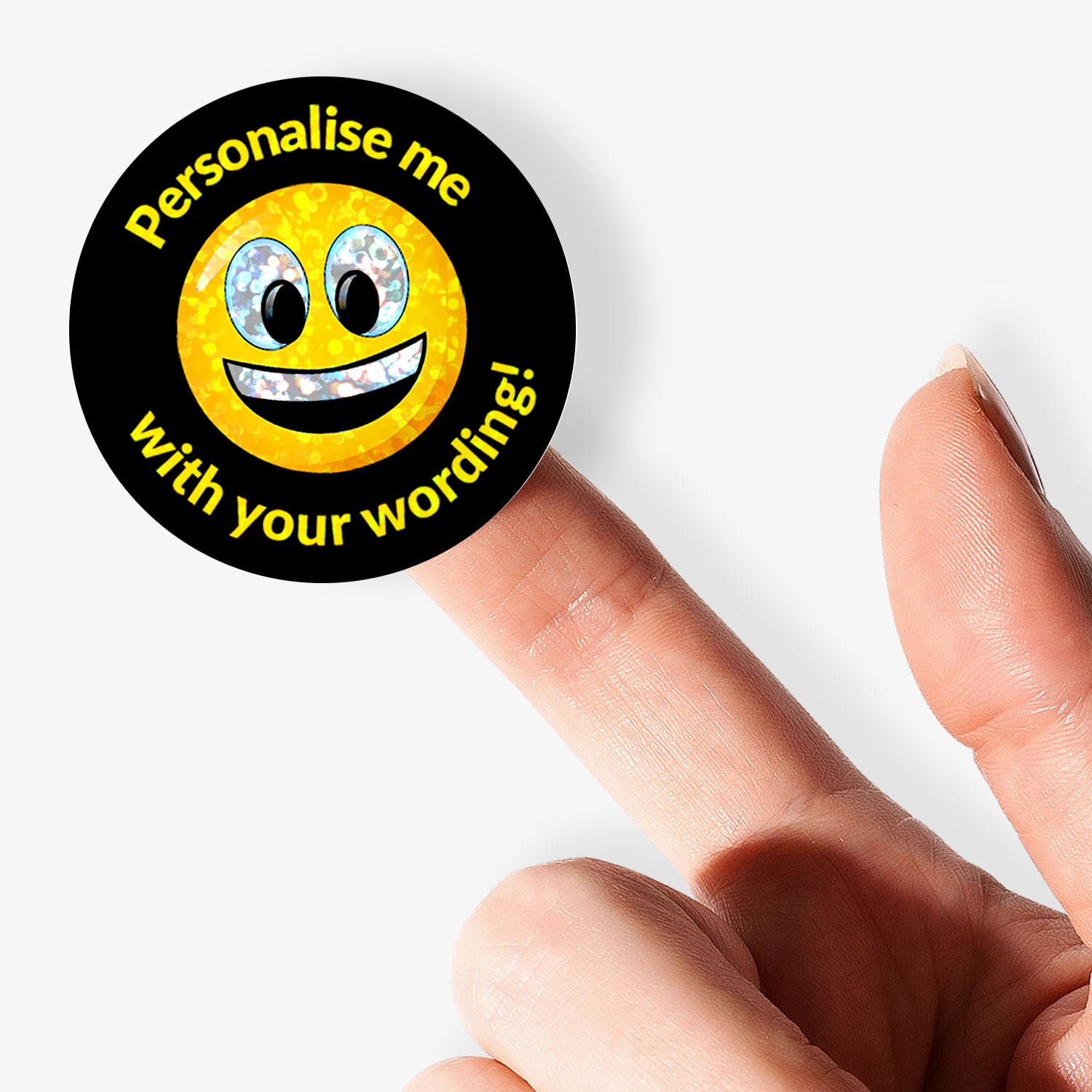 Round sticker with smiley face and text 'Personalise me with your wording!' held by a finger on a white background
