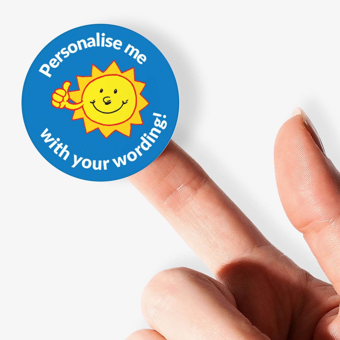 Round sticker with sun graphic and text 'Personalise me with your wording!' held between fingers.