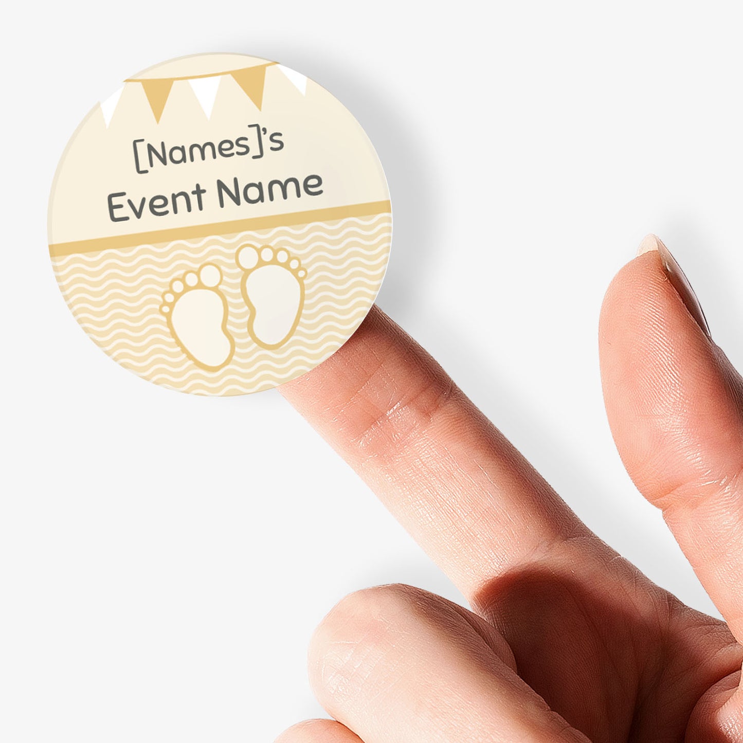 Circular sticker with cartoon baby feet and text being held by a finger