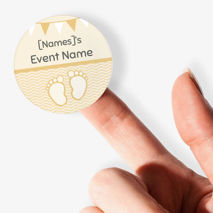 Circular sticker with cartoon baby feet and text being held by a finger