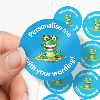 Circular blue sticker with a frog graphic and text 'Personalise me with your wording!' held by a hand.