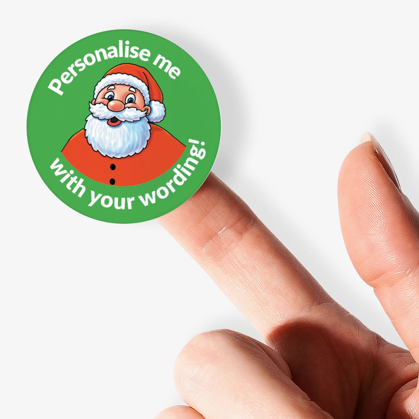 Round sticker with Santa Claus graphic and text 'Personalise me with your wording!' held between fingers.
