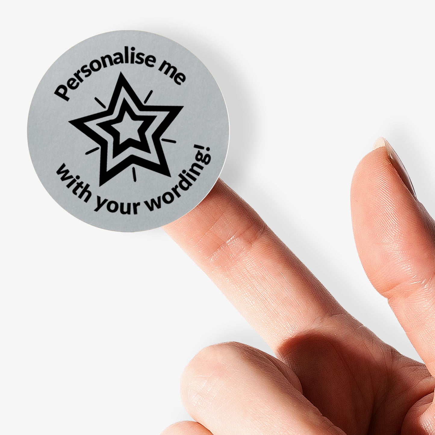Personalised round silver label with star design and text 'Personalise me with your wording!' held between fingers.