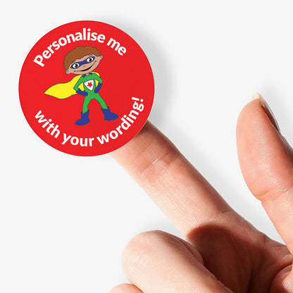 Superhero-themed personalized sticker held by a finger on a white background