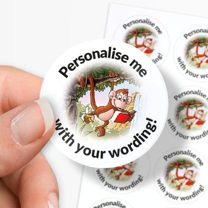 Circular sticker with cartoon monkey holding a book, text 'Personalise me with your wording!', held by a hand.