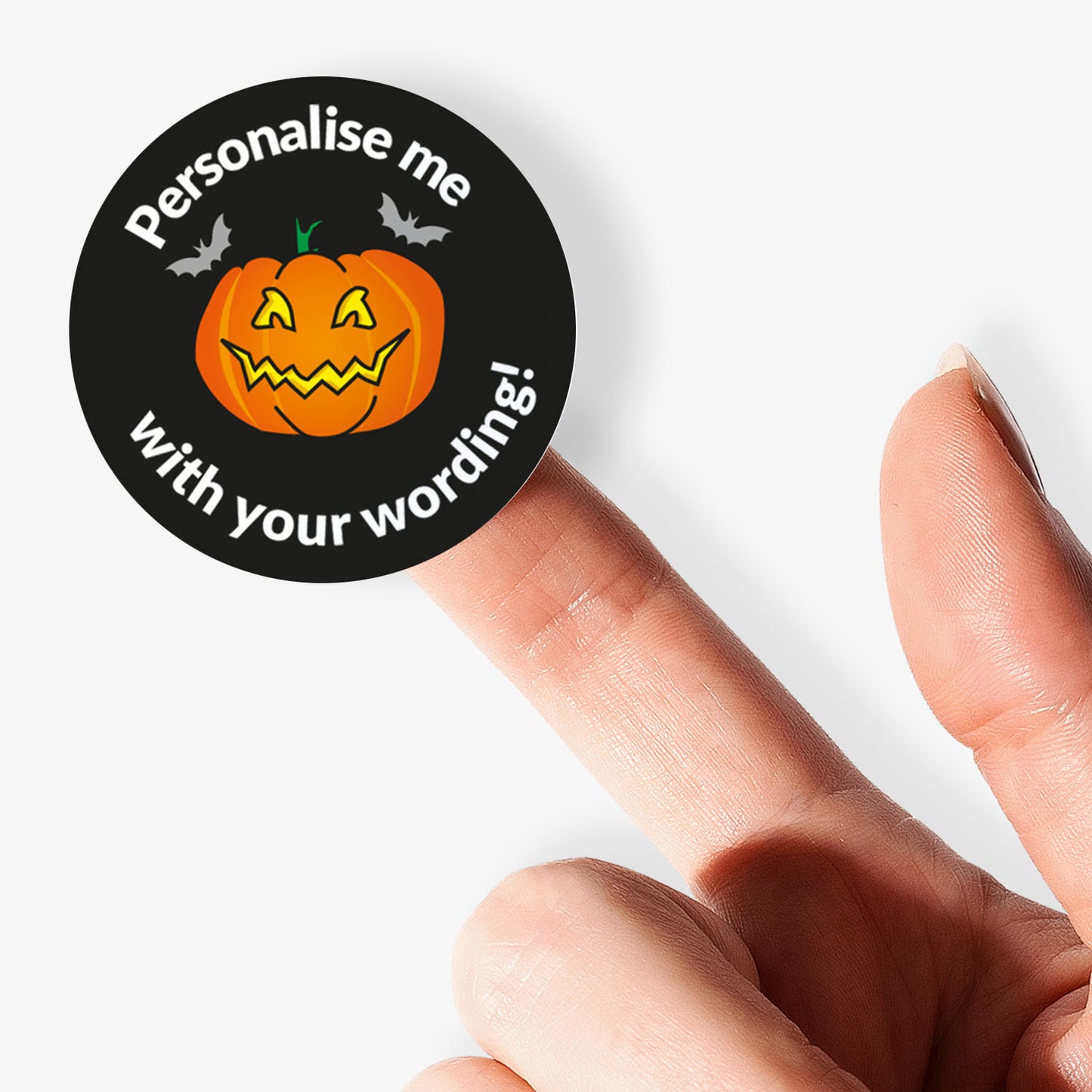 Halloween-themed sticker with a pumpkin and text 'Personalise me with your wording!' held by a finger.