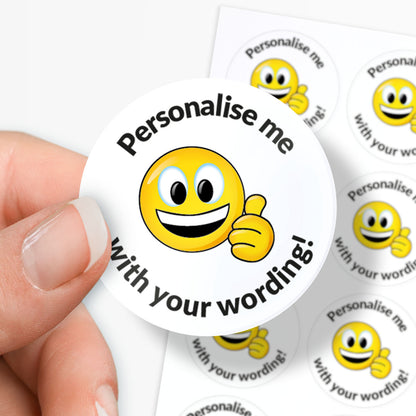 Smiley face sticker with 'Personalise me with your wording!' text held by a hand.