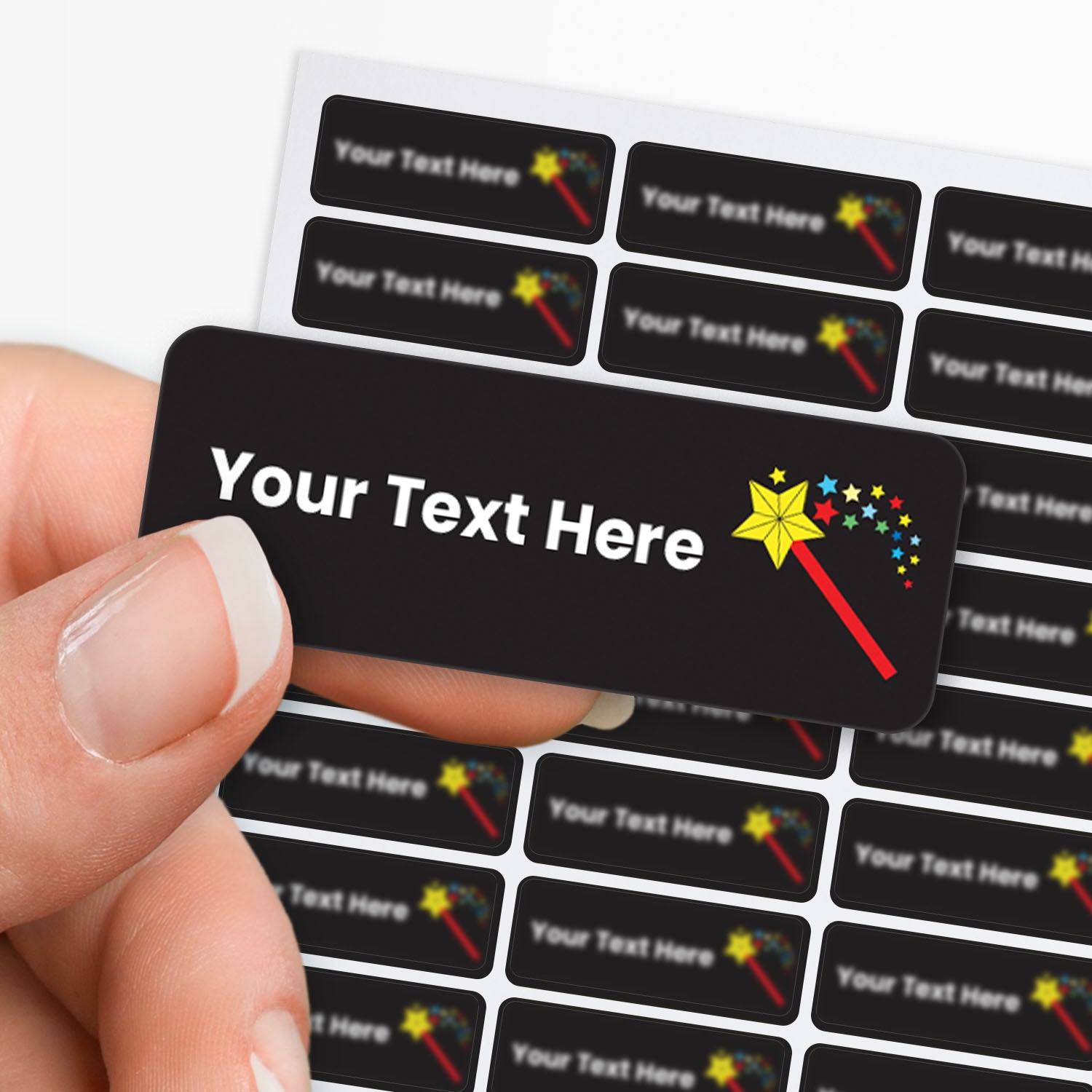 Hand holding a customizable label with text and star wand graphic, surrounded by more labels with the same design.