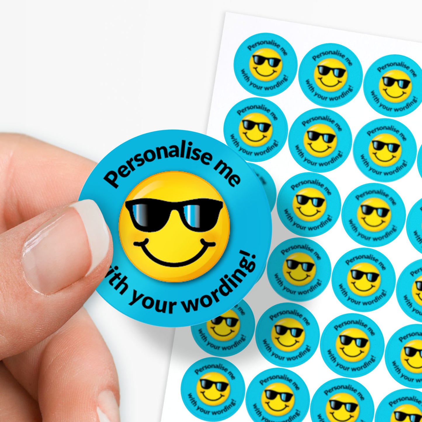 Round sticker with a smiley face wearing sunglasses and text 'Personalise me with your words!' on a blue background. Held by a finger and thumb