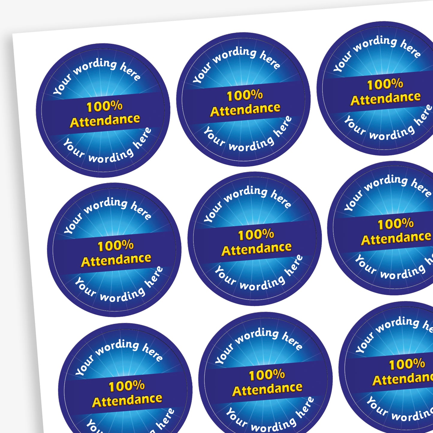 Sheet of 70 round, blue stickers, each 25mm in diameter, featuring bold yellow text reading '100% Attendance' at the centre. Surrounding the central text is placeholder wording 'Your wording here' above and below, indicating customisable areas for personalised messages.
