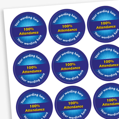 Sheet of 70 round, blue stickers, each 25mm in diameter, featuring bold yellow text reading '100% Attendance' at the centre. Surrounding the central text is placeholder wording 'Your wording here' above and below, indicating customisable areas for personalised messages.
