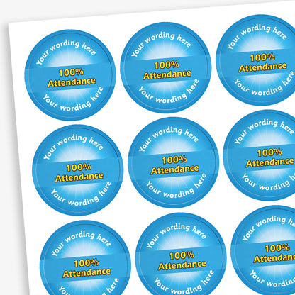 Sheet of 70 round, cyan stickers, each 25mm in diameter, featuring bold yellow text reading '100% Attendance' at the centre. Surrounding the central text is placeholder wording 'Your wording here' above and below, indicating customisable areas for personalised messages.
