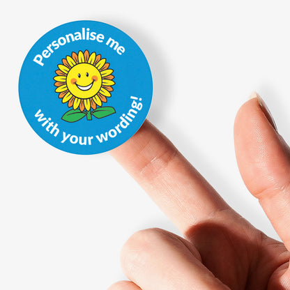 Round sticker with a sunflower design and text 'Personalise me with your wording!' held between fingers.