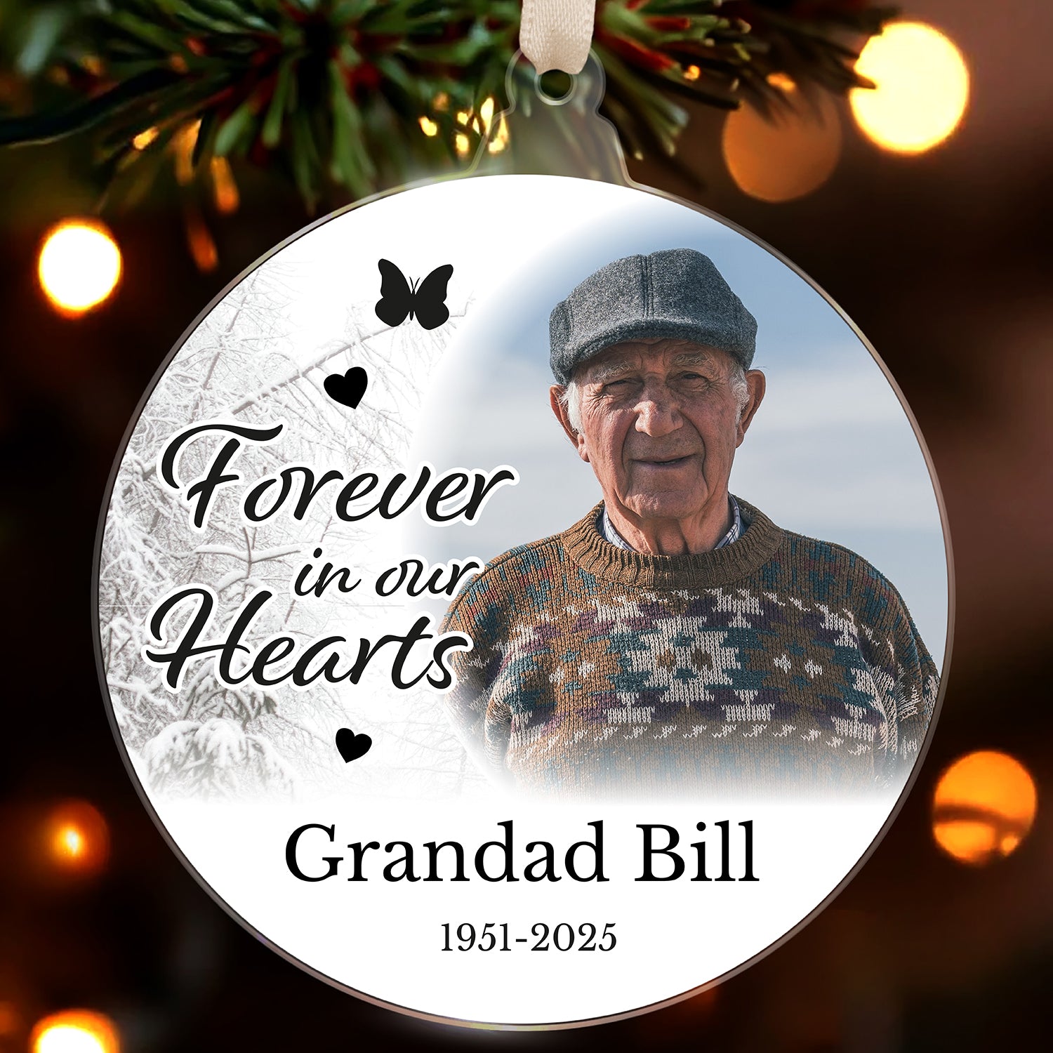Memorial ornament with an older man's photo and text 'Forever in our Hearts Grandad Bill 1951-2025' on a Christmas tree.