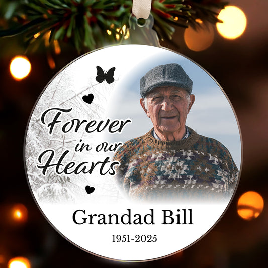 Memorial ornament with an older man's photo and text 'Forever in our Hearts Grandad Bill 1951-2025' on a Christmas tree.